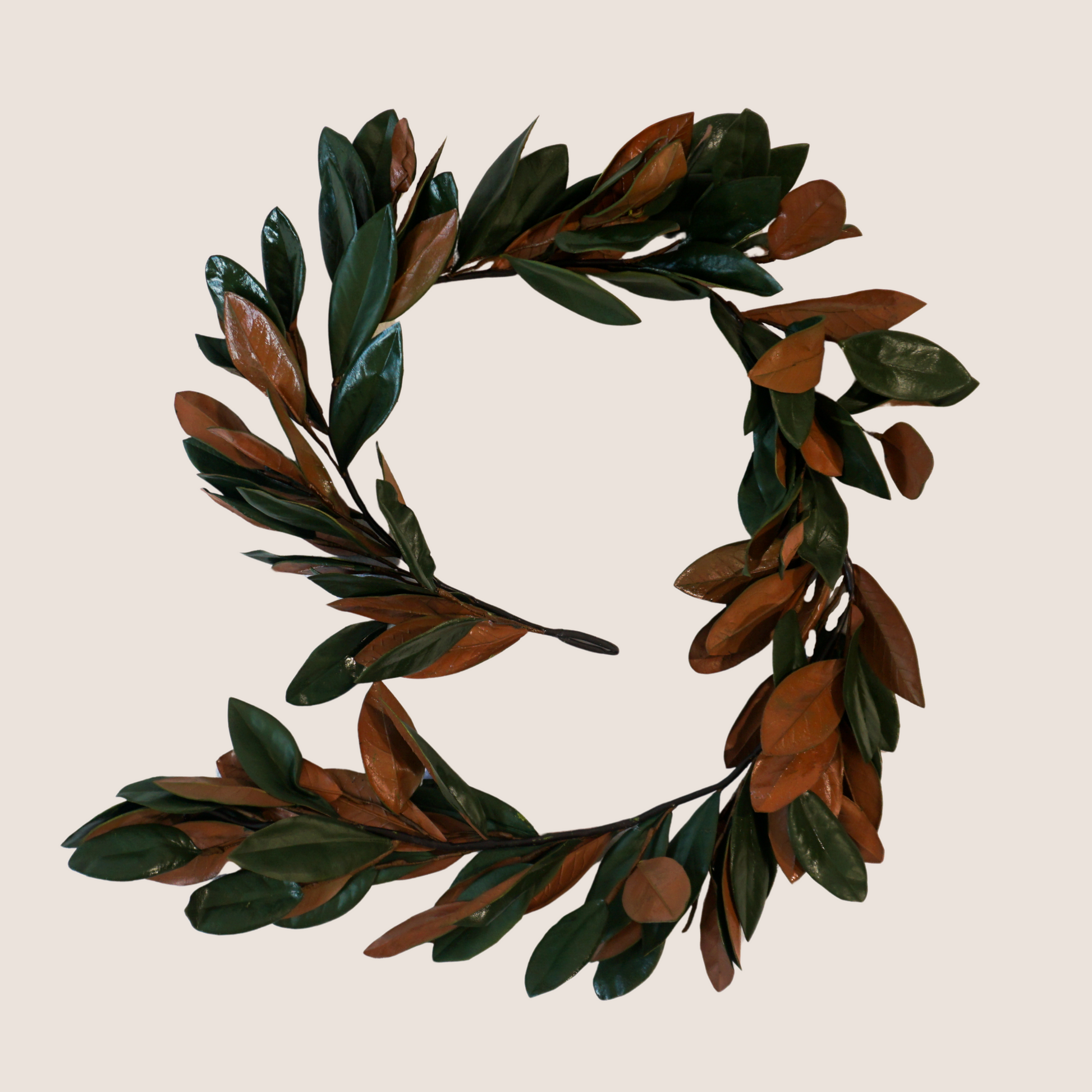 Full view of 6.5 ft. artificial magnolia leaf garland with dark green and brown leaves with a glossy finish to look preserved.