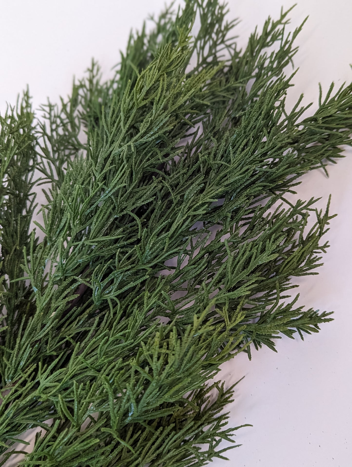 Close up picture of green gradients and density of faux cedar garland at half full density.
