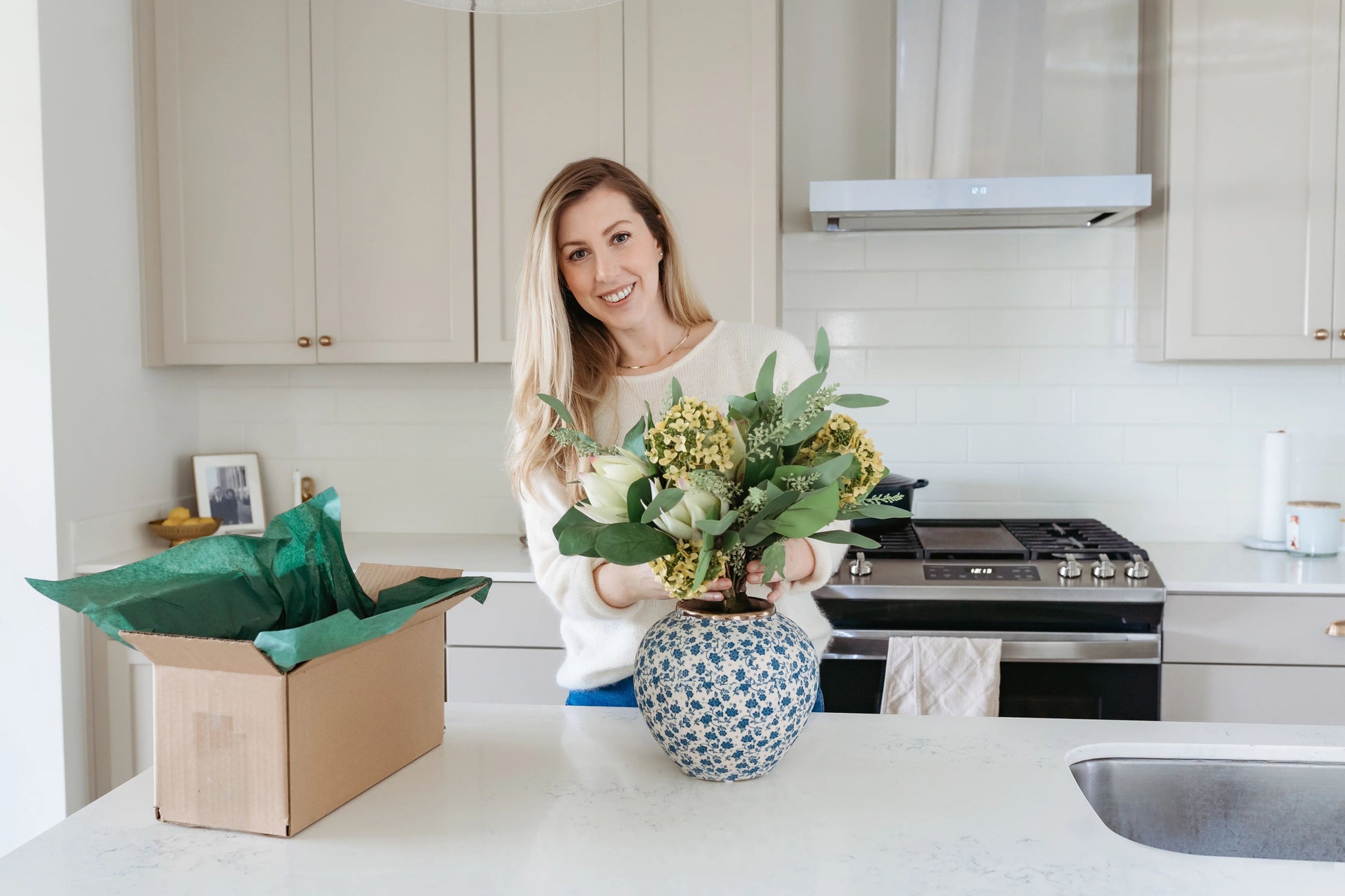 Blue ceramic floral vase being styled with artificial florals.