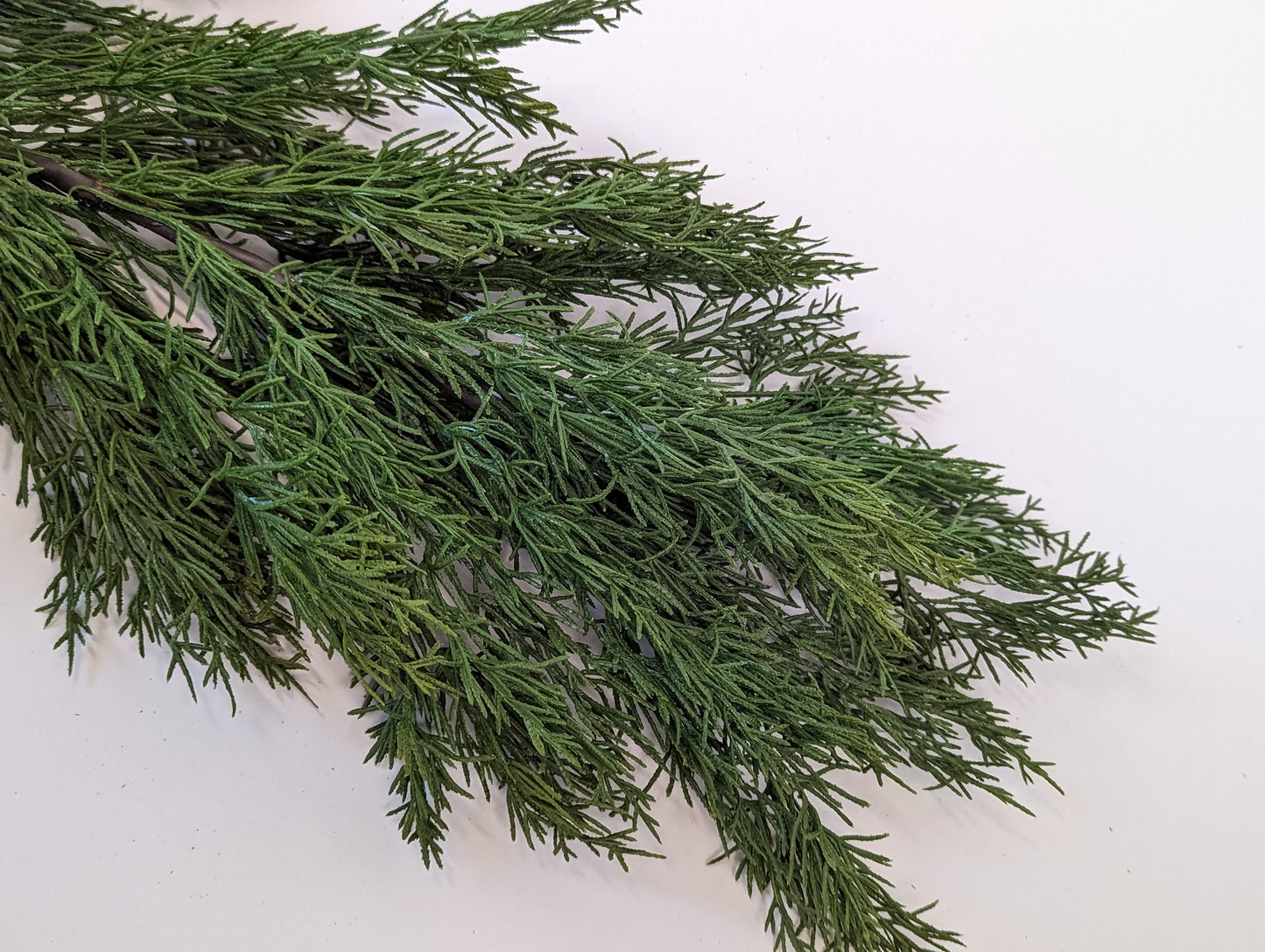 Close up picture of green gradients and density of faux cedar garland at half full density.