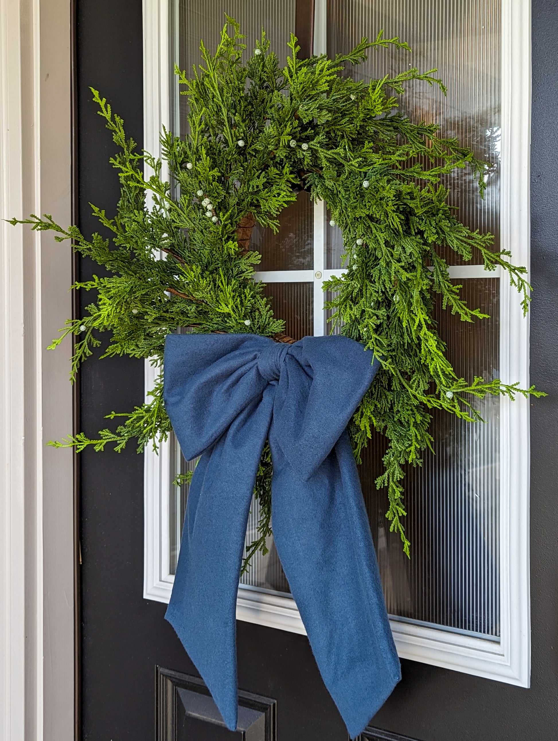 Dusty blue droopy fleece bow on juniper wreath for holiday home decorating.