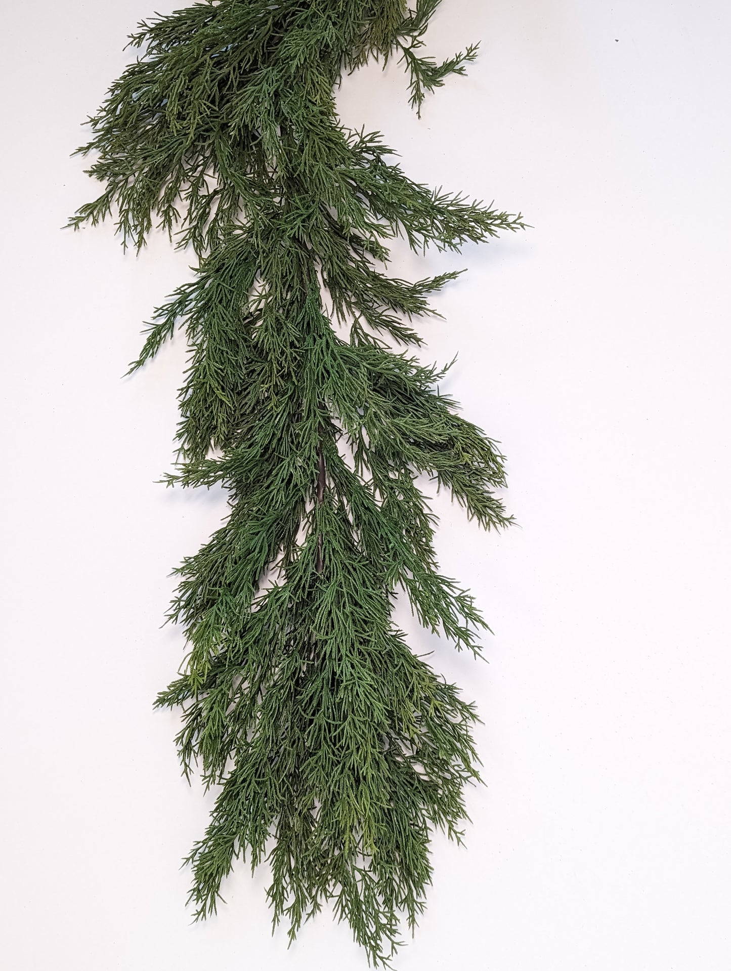 Close up picture of green gradients and density of faux cedar garland at half full density.
