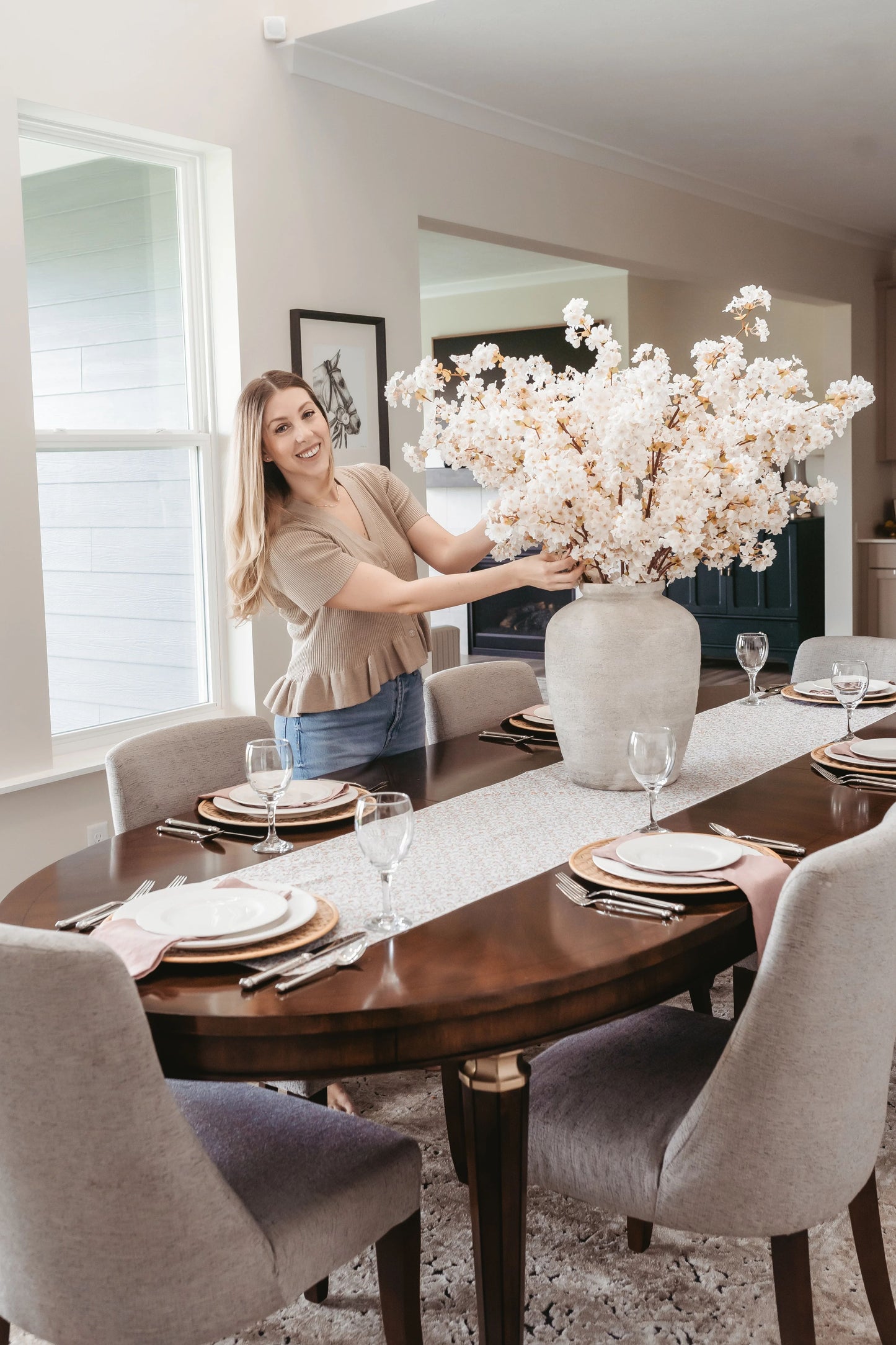 Artificial cherry blossoms being styled in large vase in dining room.