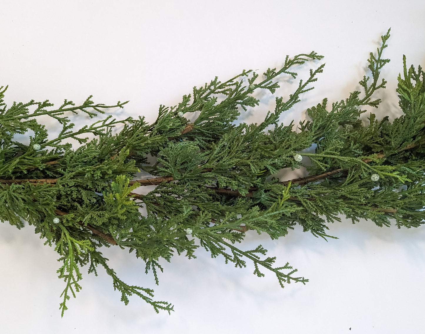 Close up of juniper cypress berry winter Christmas garland with mixed greenery and white and blue berries