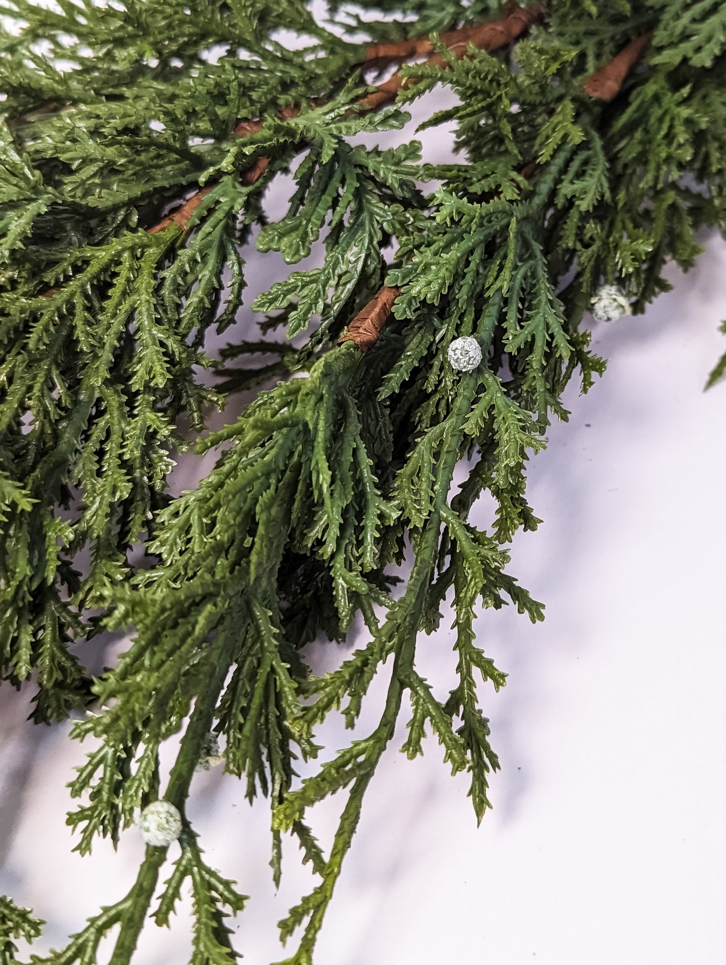 Close up of cypress berry winter garland with mixed greenery featuring white berries