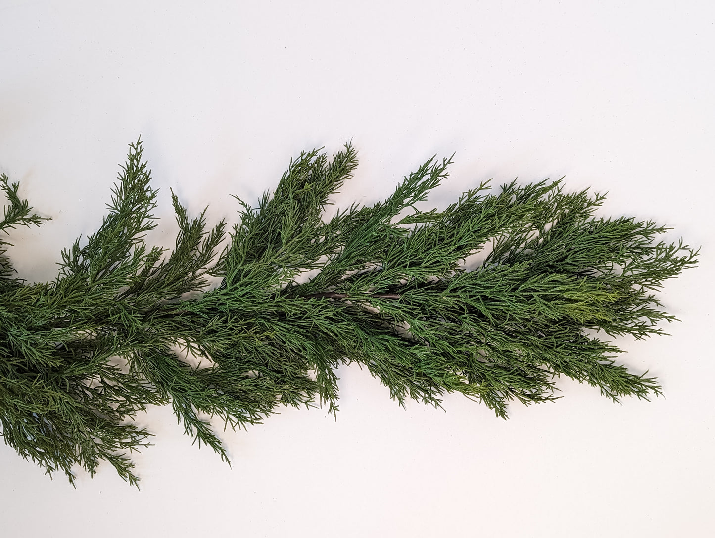 Close up picture of green gradients and density of faux cedar garland at half full density.