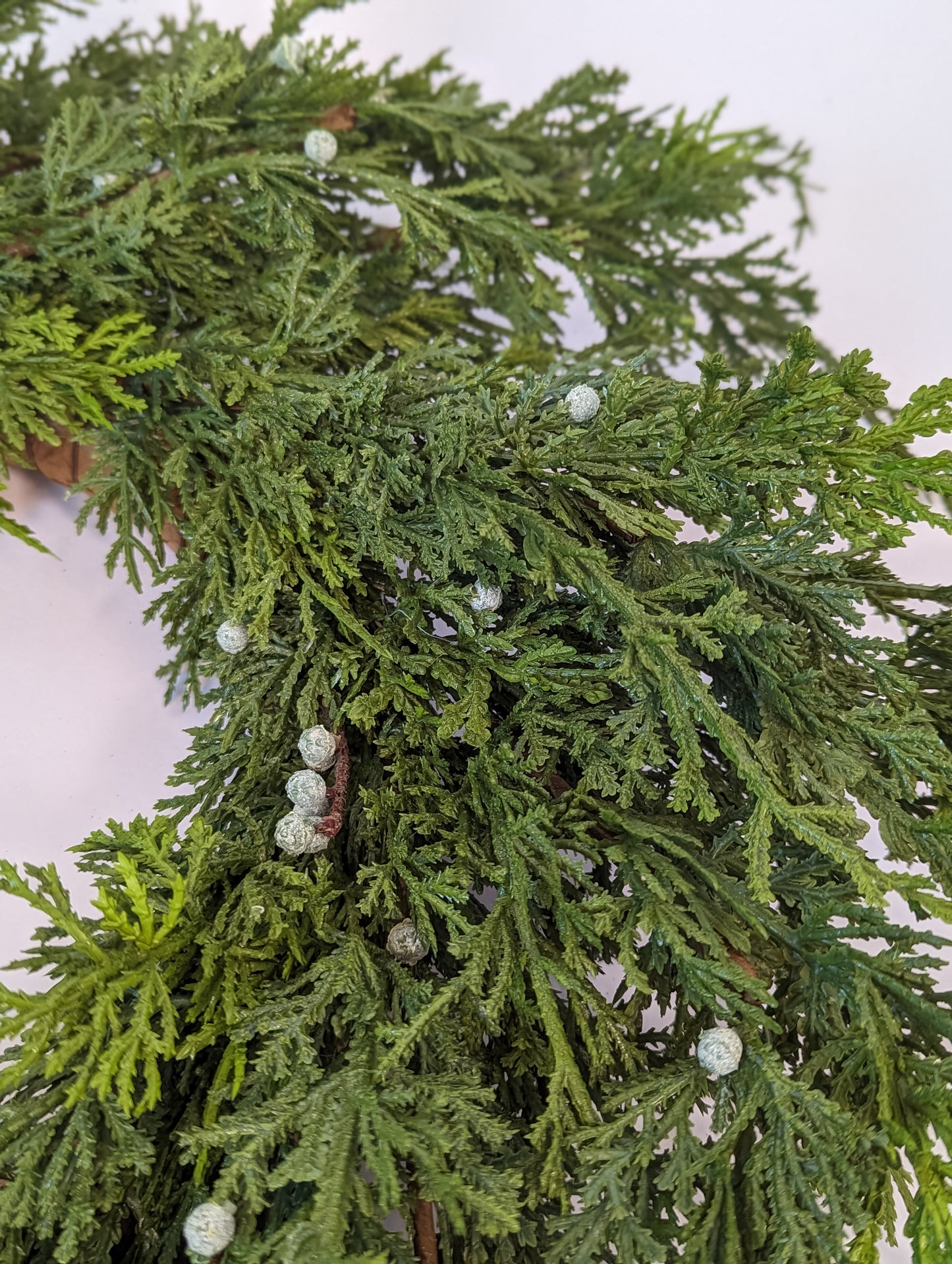 Up close picture for product feature of cypress berry wreath showcasing gradient of dark to lighter green and greenish-white berries for realistic looking artificial holiday home decor.