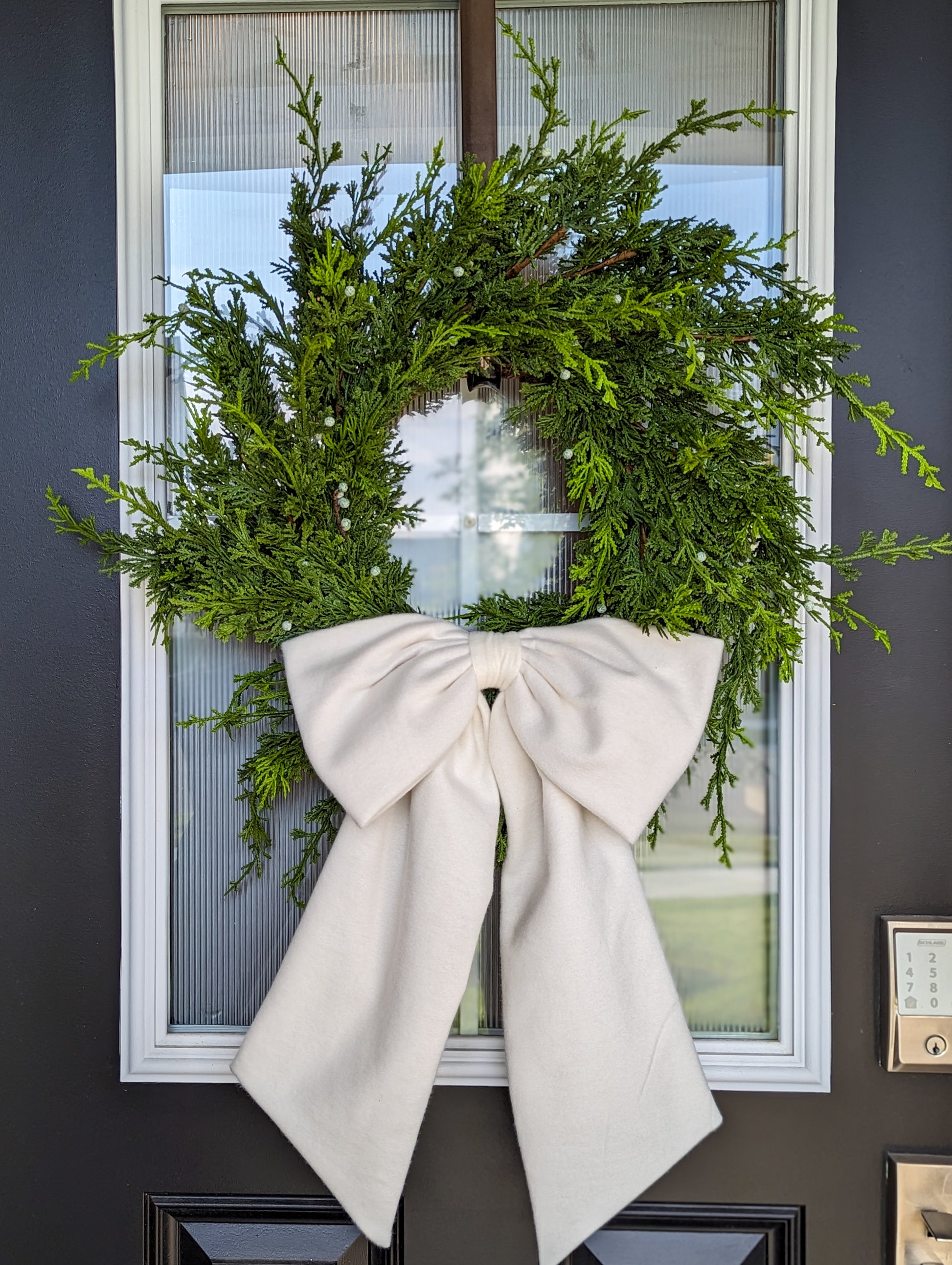 White droopy fleece bow on juniper wreath.