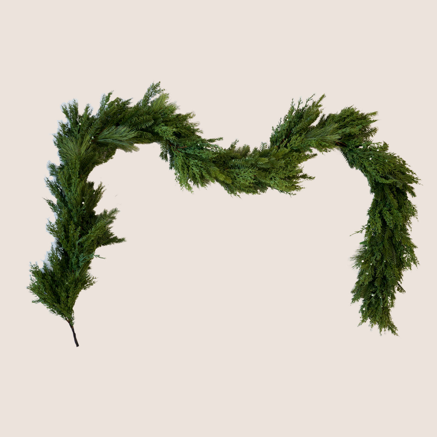 High-quality artificial garland comprised of a mixed of evergreen varieties including juniper, cedar, balsam fir, and ponderosa pine. 9 ft long garland against a blush backdrop.