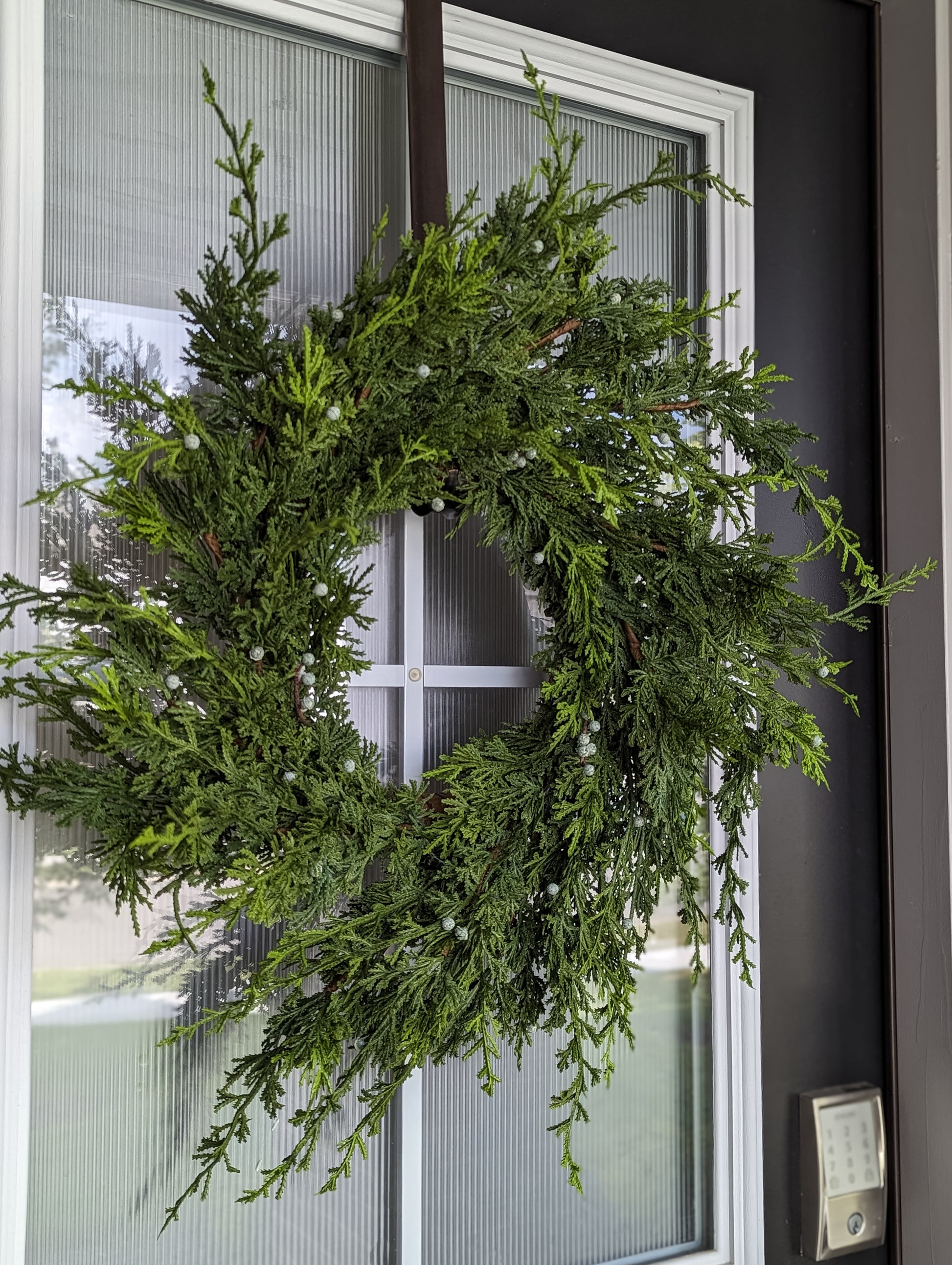 White cypress juniper berry wreath on front door for holiday home decor and front porch decorations.