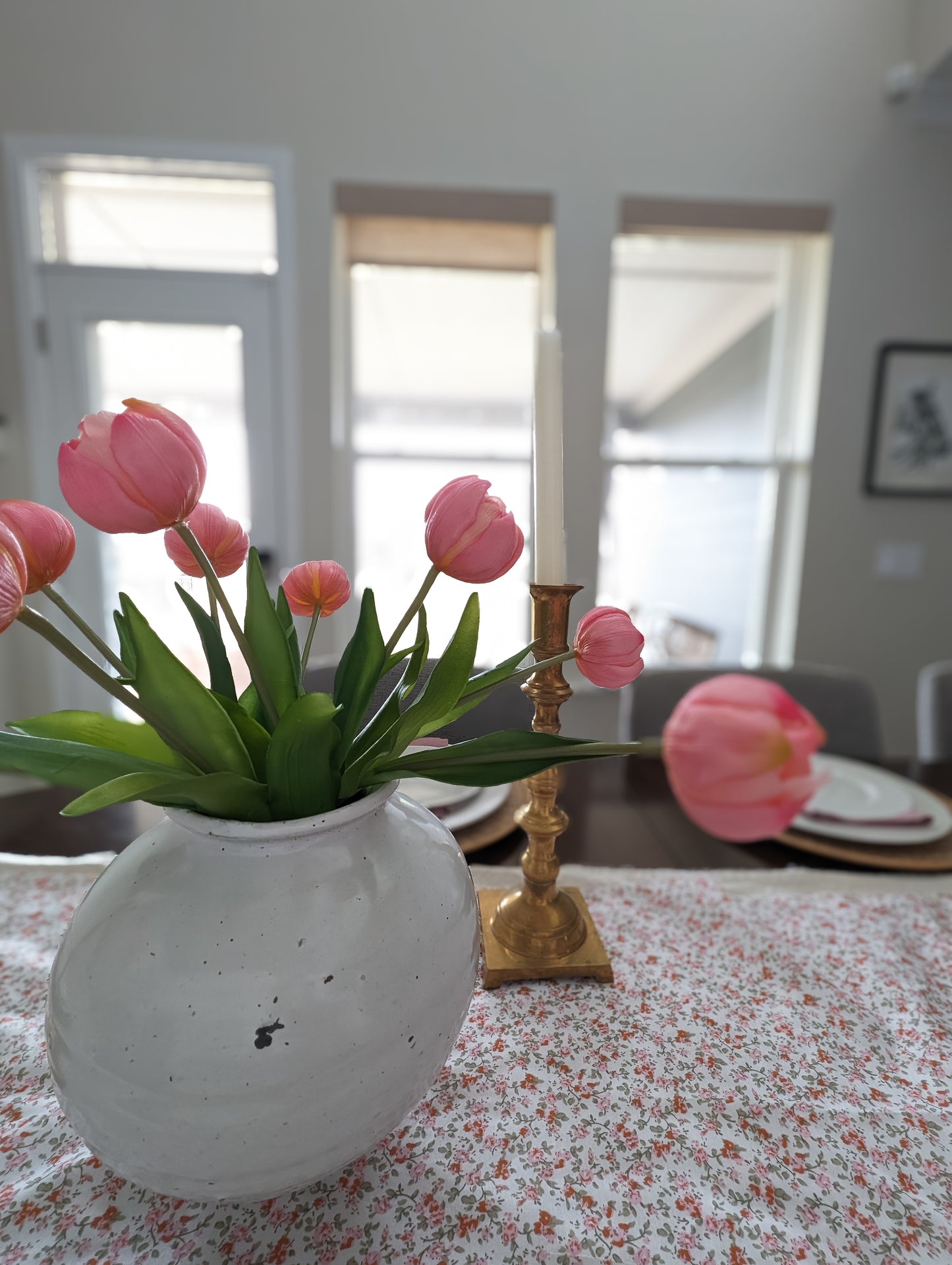Bouquet of artificial pink tulips in white vase set as part of spring tablescape. 