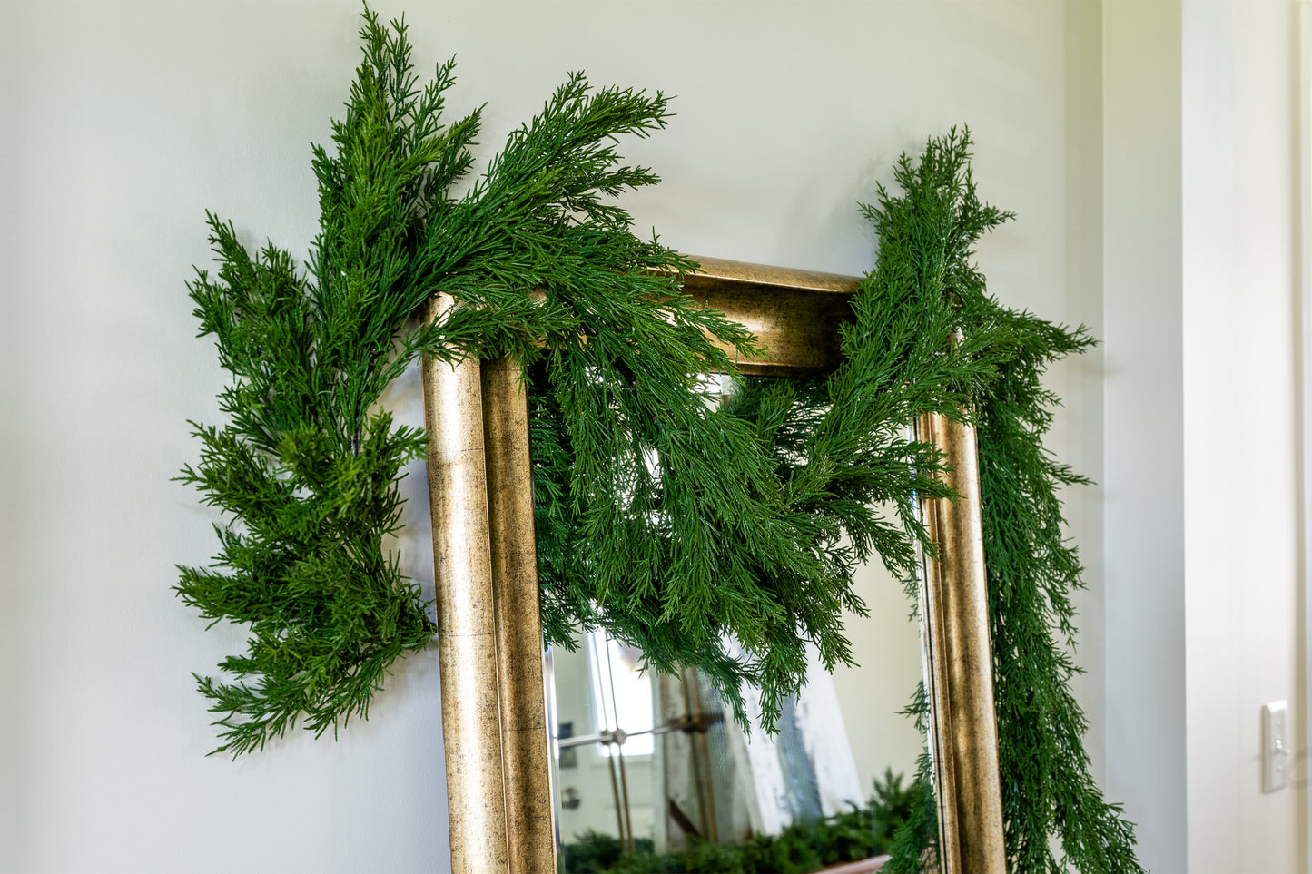 Artificial evergreen cedar garland on mirror at density of faux cedar garland at half full density.