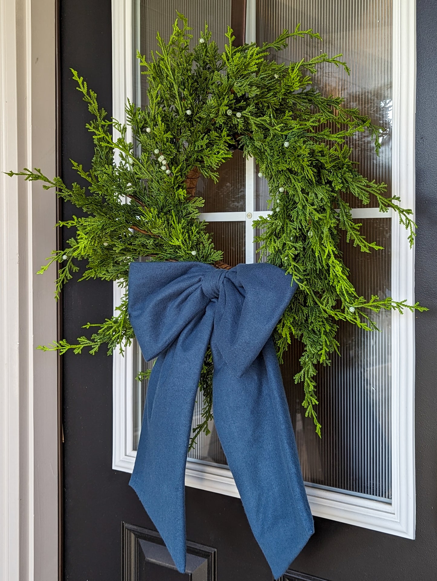 Dusty blue droopy fleece bow on juniper wreath for holiday home decorating. 