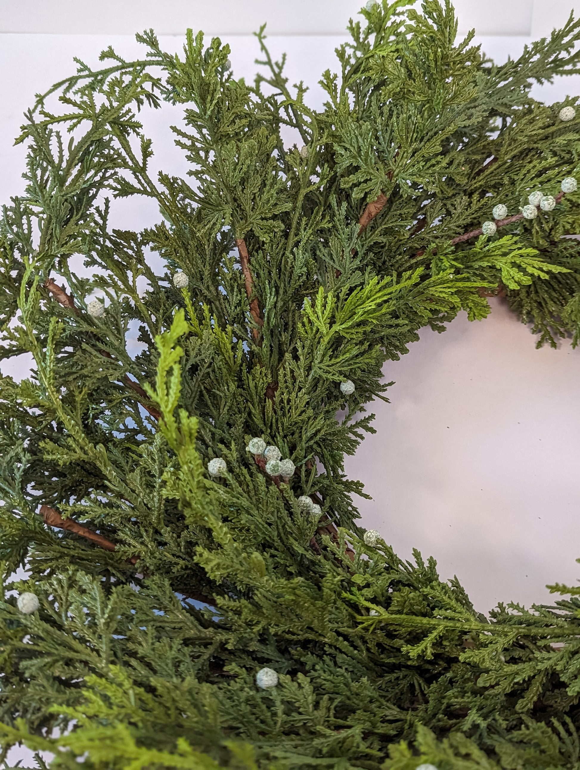 Up close picture for product feature of cypress berry wreath showcasing gradient of dark to lighter green and greenish-white berries for realistic looking artificial holiday front porch or back porch decor.