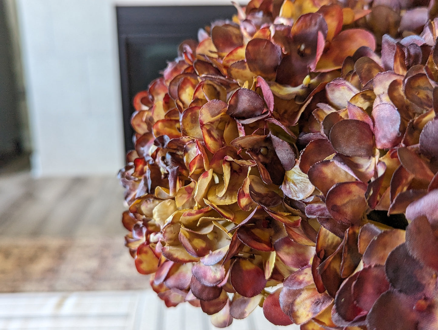 Artificial fall hydrangea flower bouquet with colors of burgundy, red, & brown petals in fluted grey vase showcasing realistic look dried florals and leaves.