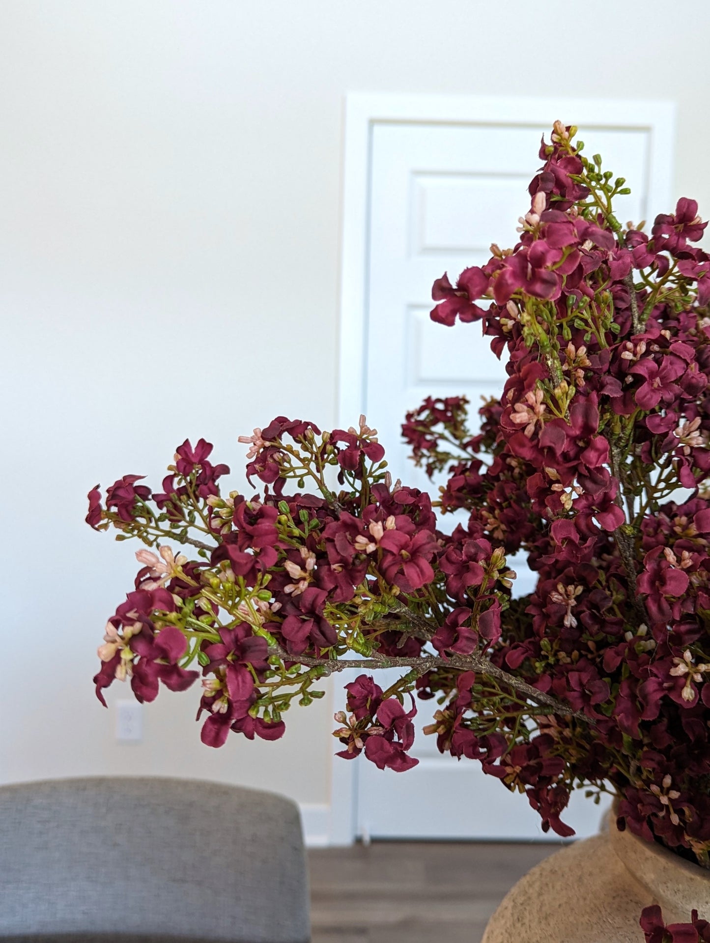 Artificial dark pink burgundy fall stem with light pink accents and realistic branch bouquet in lifestyle dining room setting.