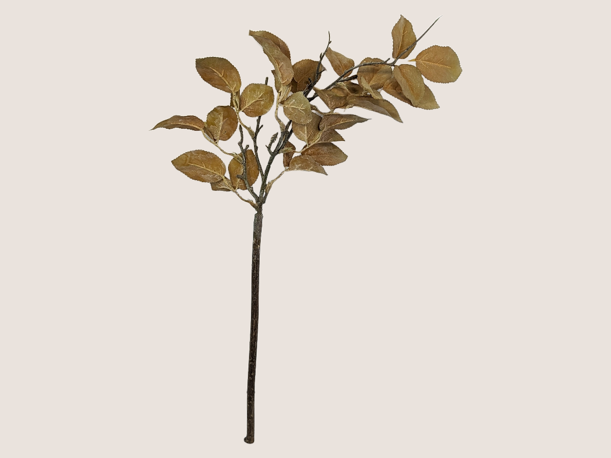 Artificial dried look golden leaf branch for fall home decor with realistic brown stem against beige background. 