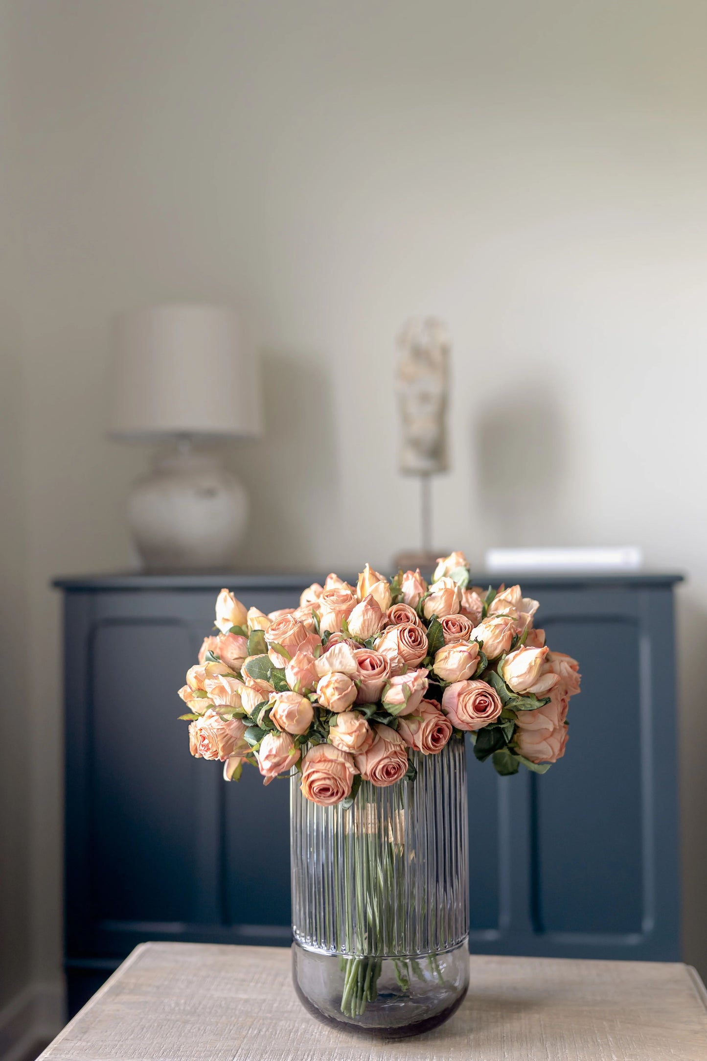 Close up of a smokey gray fluted vase, styled with preserved pink roses. 
