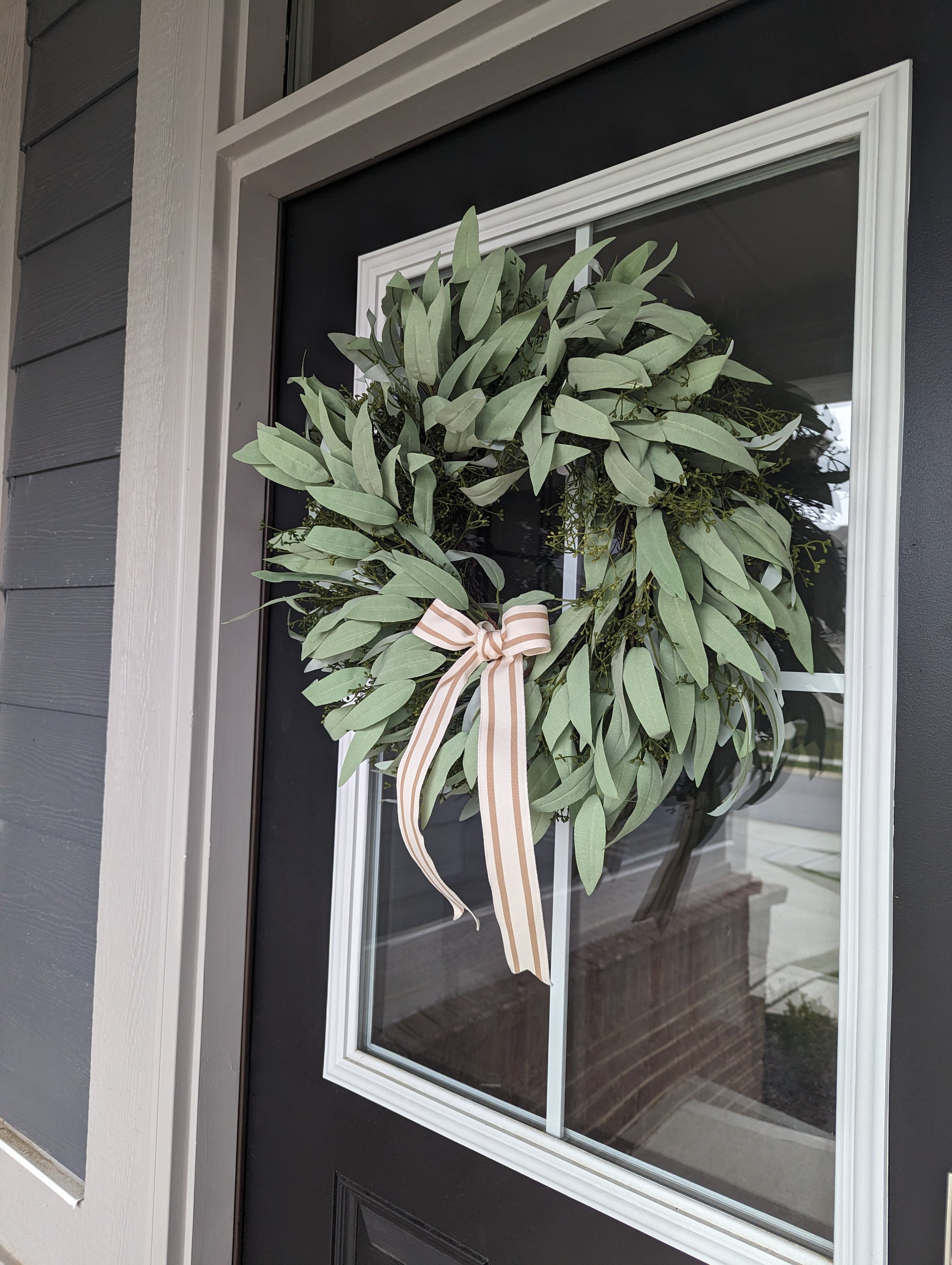 Decorate your front door with this beautiful 20-inch Artificial Seeded Eucalyptus Wreath, styled with a striped tan bow, perfect for adding a touch of lifelike greenery to your home decor this spring and summer season. This artificial wreath is a low-maintenance, long-lasting solution that looks just like the real thing. It's a perfect addition to your home decor.
