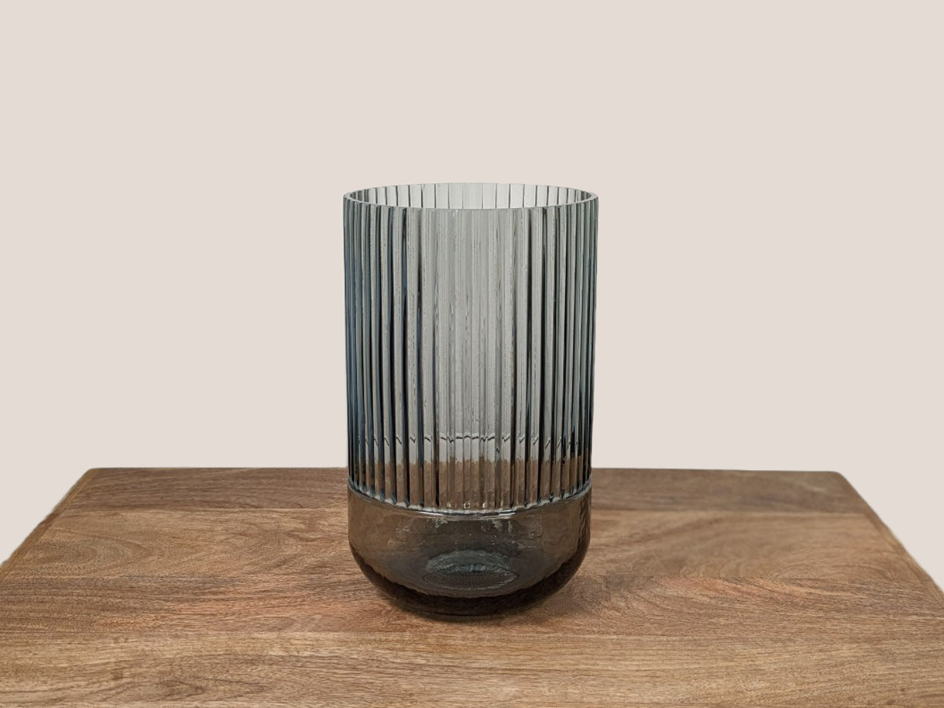 Fluted smokey grey glass vase, 9.5 inches tall. The bottom quarter of the vase is smooth glass while the top three-quarters feature fluted glass. The vase is set against a neutral beige background.