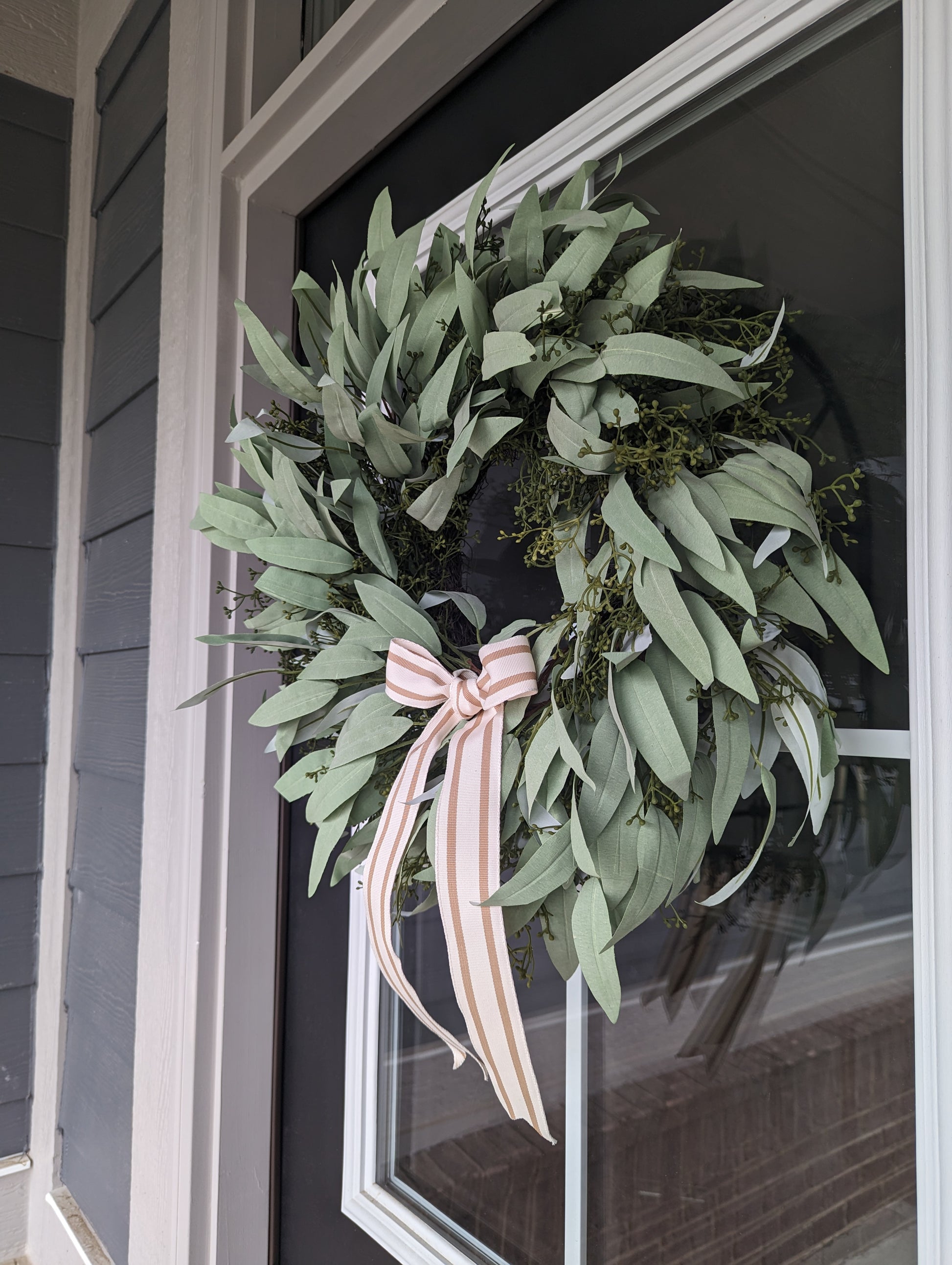20-inch Artificial Seeded Eucalyptus Wreath, featuring a stylish striped tan bow and perfect for adding a touch of lifelike greenery to your front door this spring and summer season. This artificial wreath is crafted with high-quality materials and designed to look just like the real thing. 