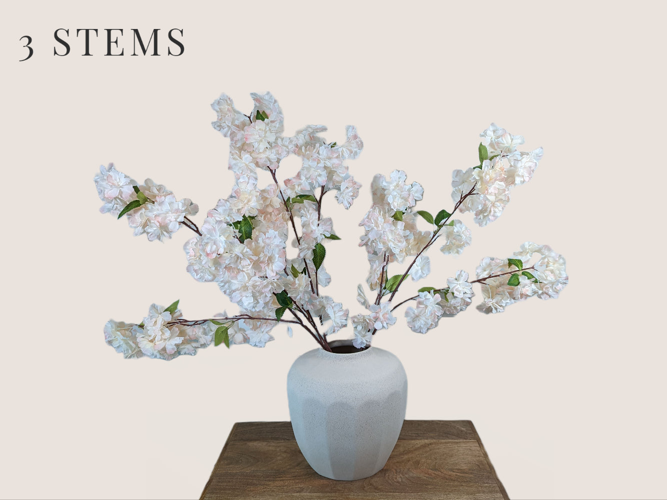 Artificial cherry blossom branches in soft pink and white, with a brown stem. Each stem has 3 branches with fully bloomed cherry blossom flowers in a big waterfall style. The arrangement is in a white vase and pictured against a neutral beige background. The total height of the arrangement is 38 inches, with 16 inches of stem and 22 inches of branch and flower.