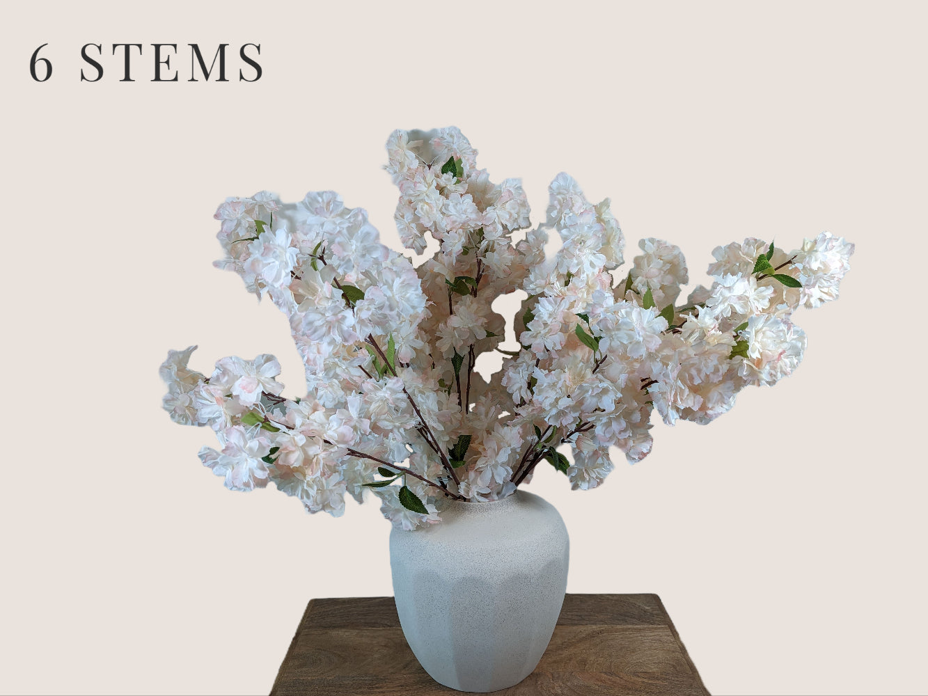 Artificial waterfall cherry blossom stems in soft pink and white, with a brown stem, each stem has 3 branches, with fully, big waterfall blossom blooms. The arrangement includes 6 branches and is displayed in a white vase. The overall height of the arrangement is 38 inches, with 16 inches of stem and 22 inches of branch/flower. The image is set against a neutral beige background.