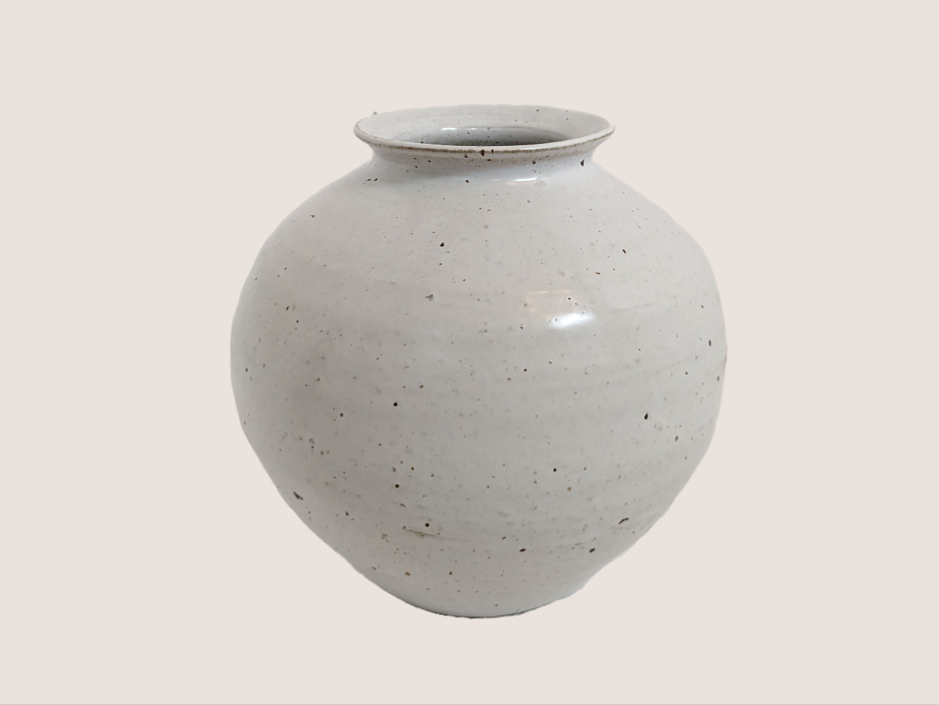 Ivory ceramic vase in round shape, 8 inches tall and 8 inches wide at largest width, with 3.5 inch vase opening. Brown and black speckles give it natural texture and look. 